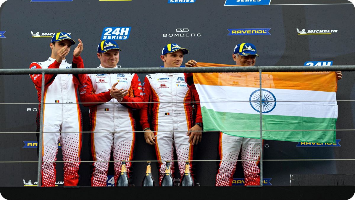 Actor Ajith Kumar holding the Indian flag on the podium at Circuit de Spa-Francorchamps, Belgium.