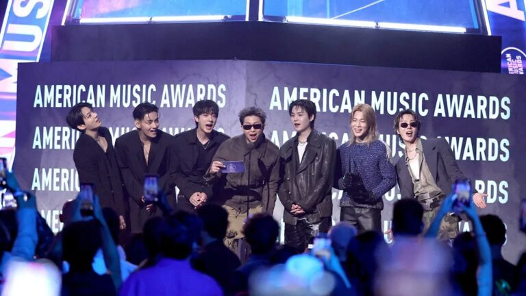 Global K-pop group BTS holding their three trophies, including Artist of the Year, at the American Music Awards 2026 stage in Las Vegas.