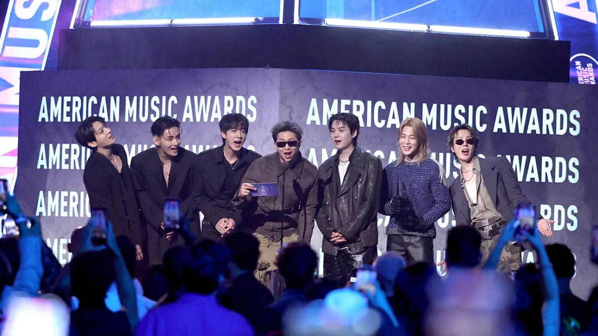 Global K-pop group BTS holding their three trophies, including Artist of the Year, at the American Music Awards 2026 stage in Las Vegas.